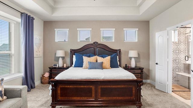 carpeted bedroom with connected bathroom and a raised ceiling