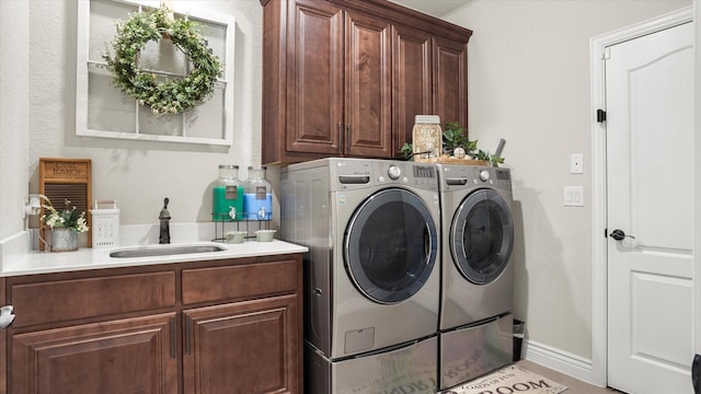 laundry room featuring washer and dryer, cabinets, and sink