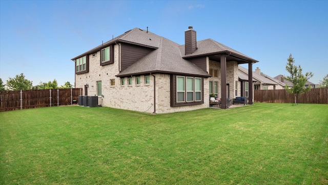 rear view of property featuring central air condition unit and a yard