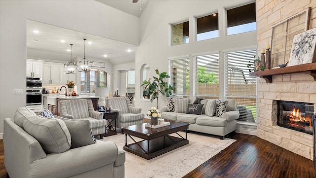 living room featuring dark hardwood / wood-style floors, a healthy amount of sunlight, a stone fireplace, and sink