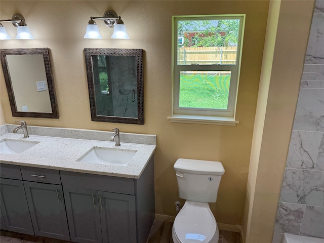 bathroom with oversized vanity, double sink, and toilet