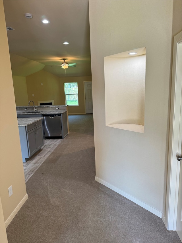 interior space with lofted ceiling, ceiling fan, sink, dishwasher, and dark carpet