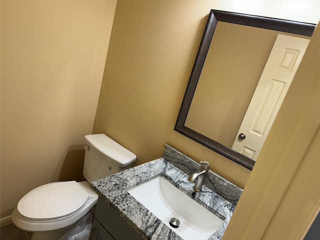 bathroom with tile floors, vanity, and toilet