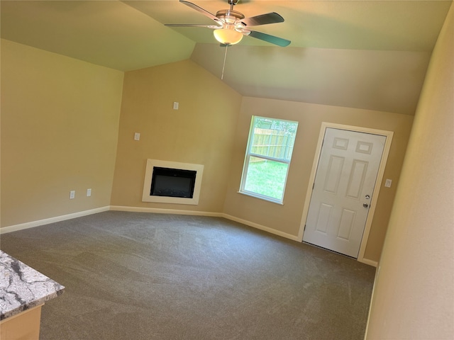 unfurnished living room with ceiling fan, lofted ceiling, and dark carpet