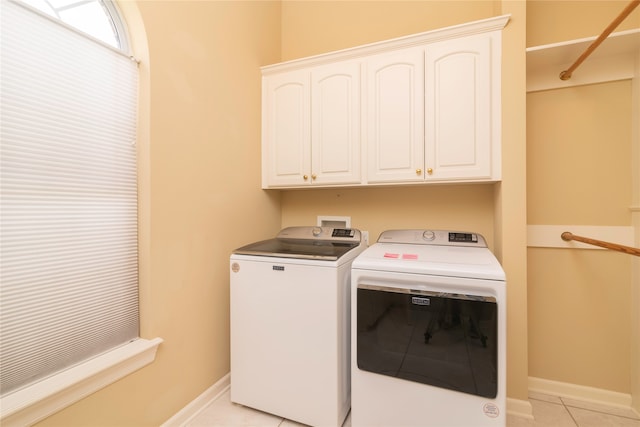 laundry area with washing machine and dryer, cabinets, and light tile patterned floors