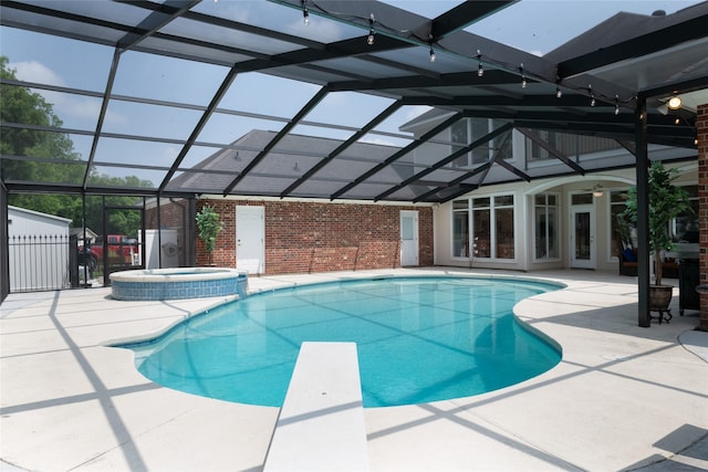 view of swimming pool with a diving board, a lanai, an in ground hot tub, a patio area, and french doors