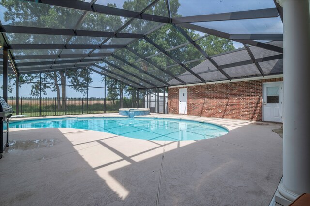 view of pool featuring an in ground hot tub, glass enclosure, and a patio