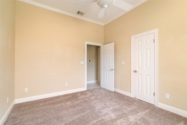 spare room with ceiling fan, crown molding, and light carpet