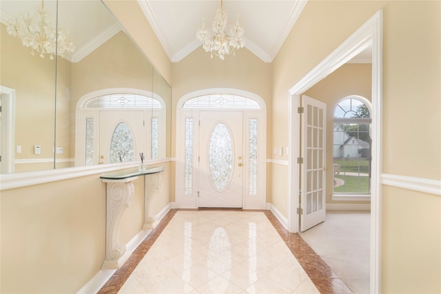 tiled foyer entrance featuring high vaulted ceiling, crown molding, and a notable chandelier