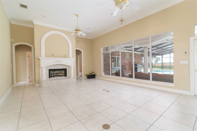 unfurnished living room featuring ceiling fan, ornamental molding, a tile fireplace, and light tile patterned floors