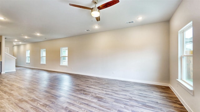 empty room with plenty of natural light, ceiling fan, and light hardwood / wood-style flooring