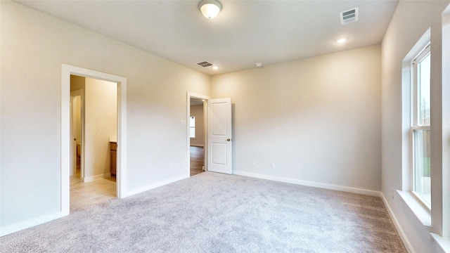 unfurnished bedroom featuring light carpet, visible vents, and baseboards