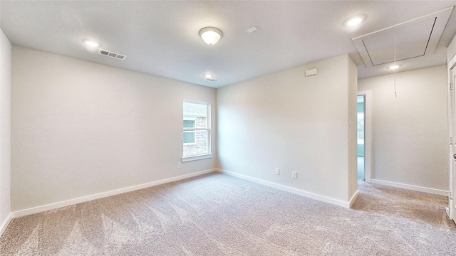 spare room with visible vents, carpet floors, attic access, and baseboards