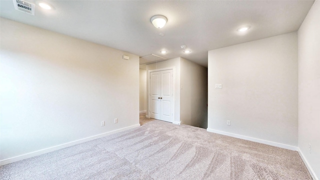 spare room featuring attic access, visible vents, carpet floors, and baseboards