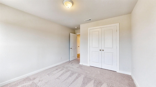 unfurnished bedroom featuring light carpet and a closet