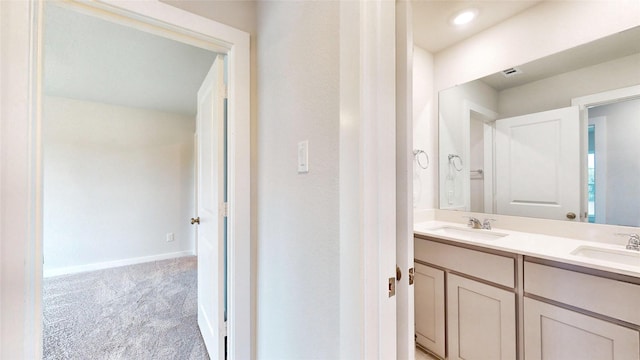 bathroom with double vanity, a sink, and baseboards