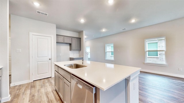 kitchen with a sink, visible vents, stainless steel dishwasher, light wood-type flooring, and gray cabinets