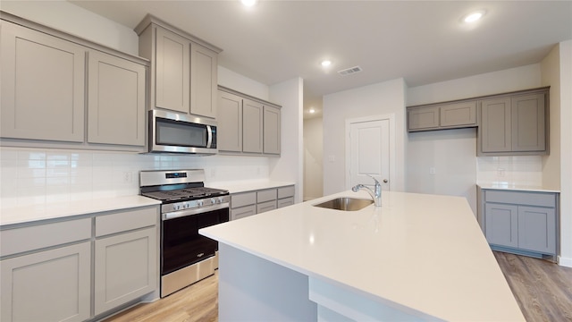 kitchen featuring gray cabinetry, sink, light hardwood / wood-style flooring, and appliances with stainless steel finishes