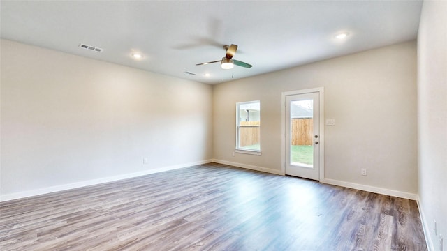 unfurnished room featuring baseboards, visible vents, ceiling fan, and wood finished floors