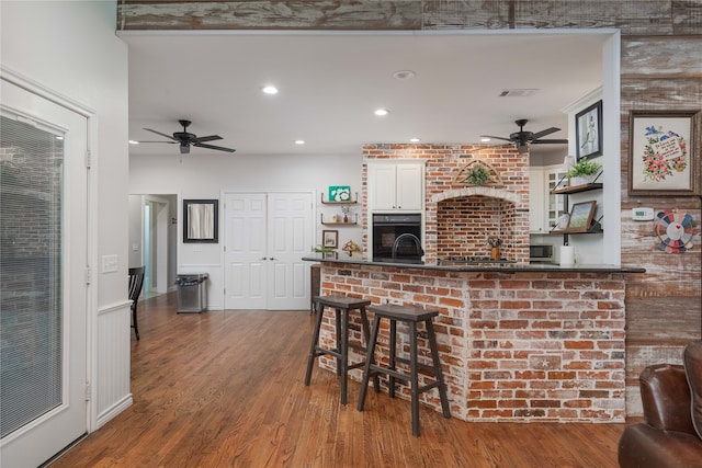 bar featuring white cabinets, black oven, hardwood / wood-style flooring, and ceiling fan