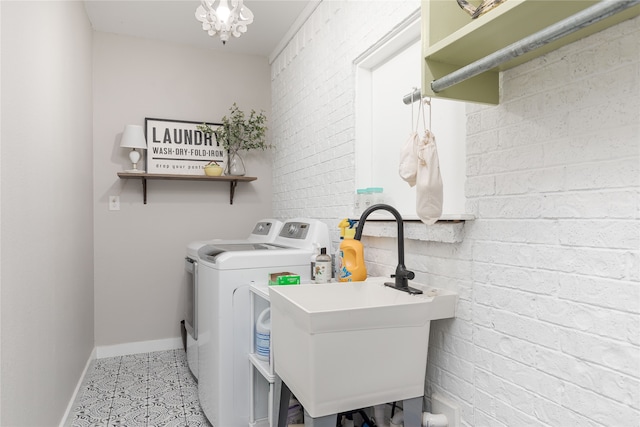 clothes washing area featuring brick wall, sink, independent washer and dryer, and tile floors