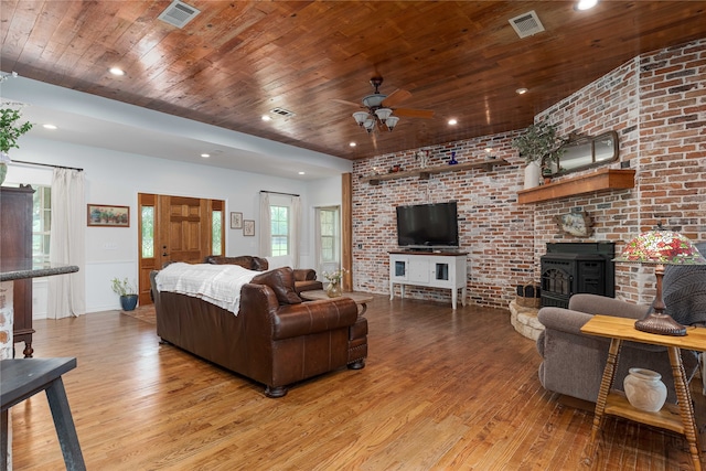 living room featuring wood ceiling, brick wall, a wood stove, and wood-type flooring