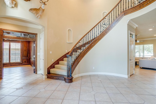 foyer featuring a towering ceiling, tile flooring, ceiling fan, and crown molding