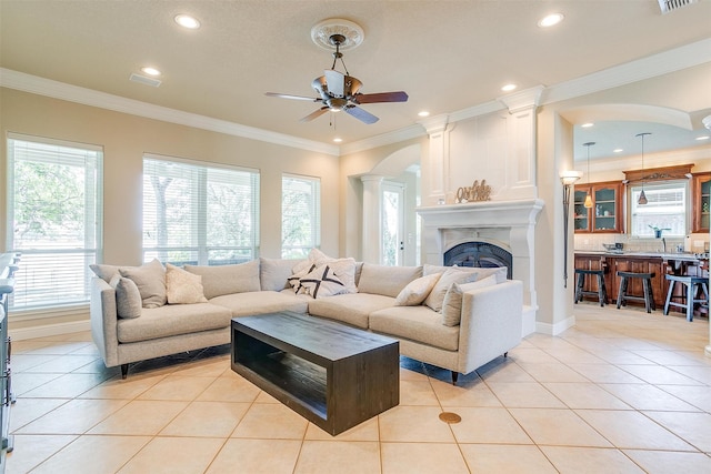 tiled living room featuring plenty of natural light, ornamental molding, and ceiling fan