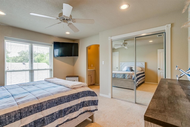 carpeted bedroom featuring a closet, ceiling fan, and a textured ceiling