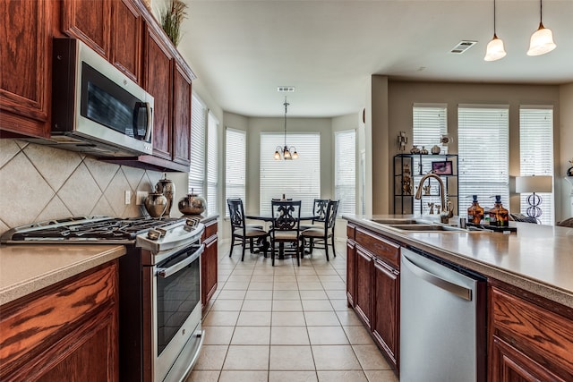 kitchen with a chandelier, stainless steel appliances, plenty of natural light, and hanging light fixtures