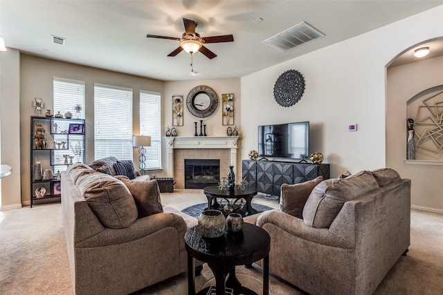 carpeted living room with a tile fireplace and ceiling fan