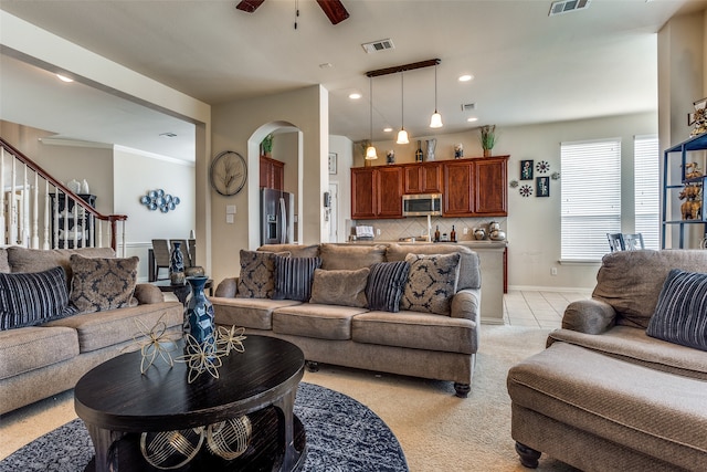 living room with ceiling fan, light colored carpet, and crown molding