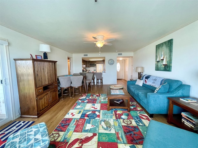 living room featuring hardwood / wood-style floors, ornamental molding, and ceiling fan