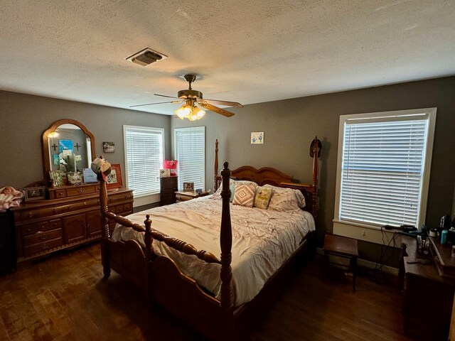 bedroom featuring dark hardwood / wood-style floors, ceiling fan, and a textured ceiling