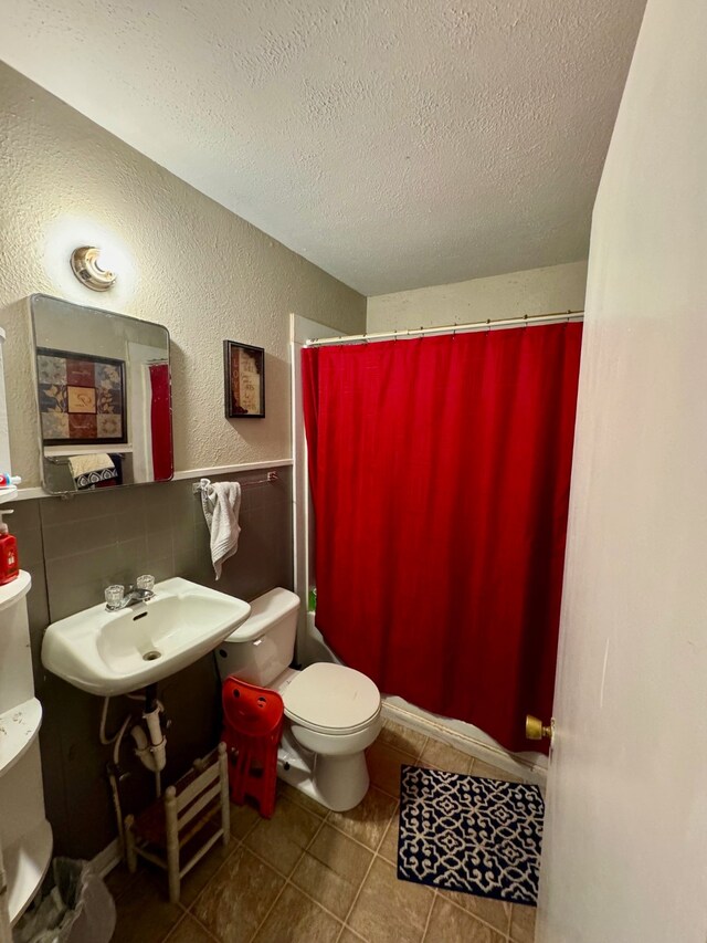 bathroom featuring tile flooring, tasteful backsplash, a textured ceiling, sink, and toilet