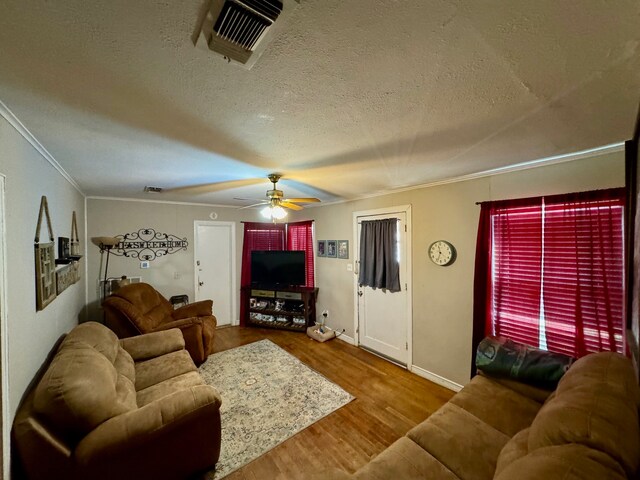 living room featuring ceiling fan, hardwood / wood-style flooring, a textured ceiling, and crown molding