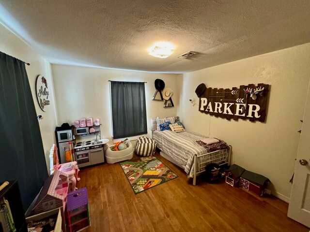 bedroom featuring hardwood / wood-style flooring and a textured ceiling