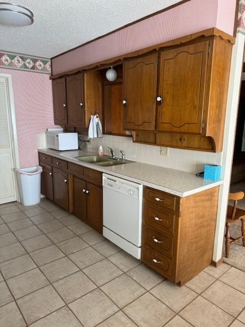 kitchen with sink, white appliances, light tile patterned floors, and a textured ceiling