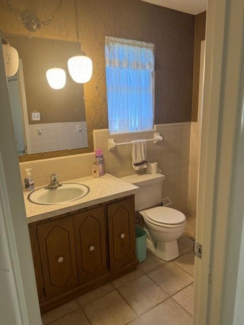 bathroom featuring vanity, toilet, tile walls, and tile patterned floors