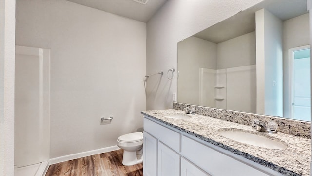 bathroom with hardwood / wood-style flooring, vanity, walk in shower, and toilet