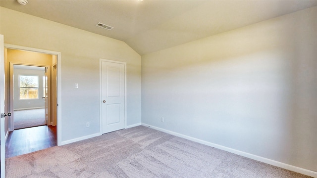 unfurnished bedroom featuring light colored carpet, a closet, and vaulted ceiling