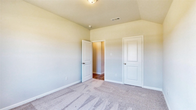 unfurnished bedroom with light colored carpet and vaulted ceiling