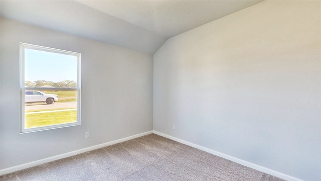 spare room featuring vaulted ceiling and carpet flooring