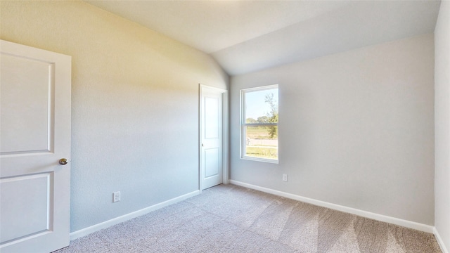 carpeted spare room featuring lofted ceiling