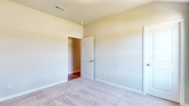 unfurnished bedroom with lofted ceiling and carpet flooring