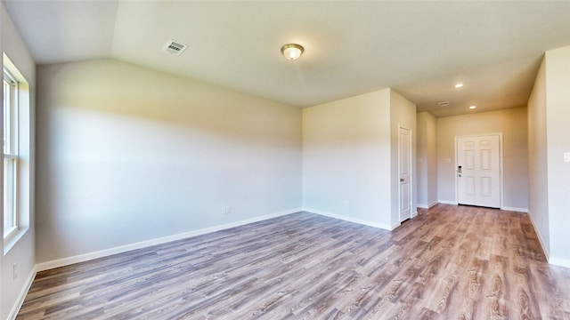 empty room featuring light wood-type flooring and vaulted ceiling