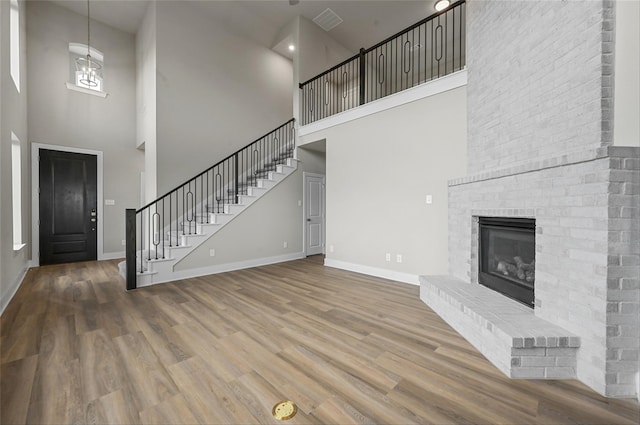 unfurnished living room featuring wood-type flooring, a fireplace, and a high ceiling