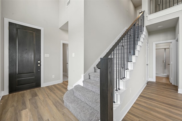 foyer entrance with wood-type flooring and a towering ceiling