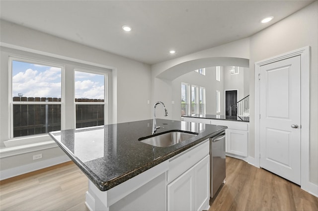 kitchen with sink, white cabinetry, a center island with sink, dishwasher, and dark stone counters