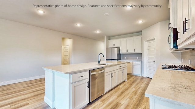 kitchen with backsplash, appliances with stainless steel finishes, an island with sink, and light hardwood / wood-style floors